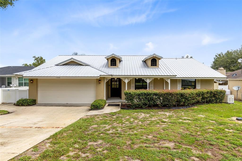 A single-story house with a metal roof, two dormer windows, and a front-facing garage — 17531 N SUNSET TERRACE, WINTER GARDEN, FL