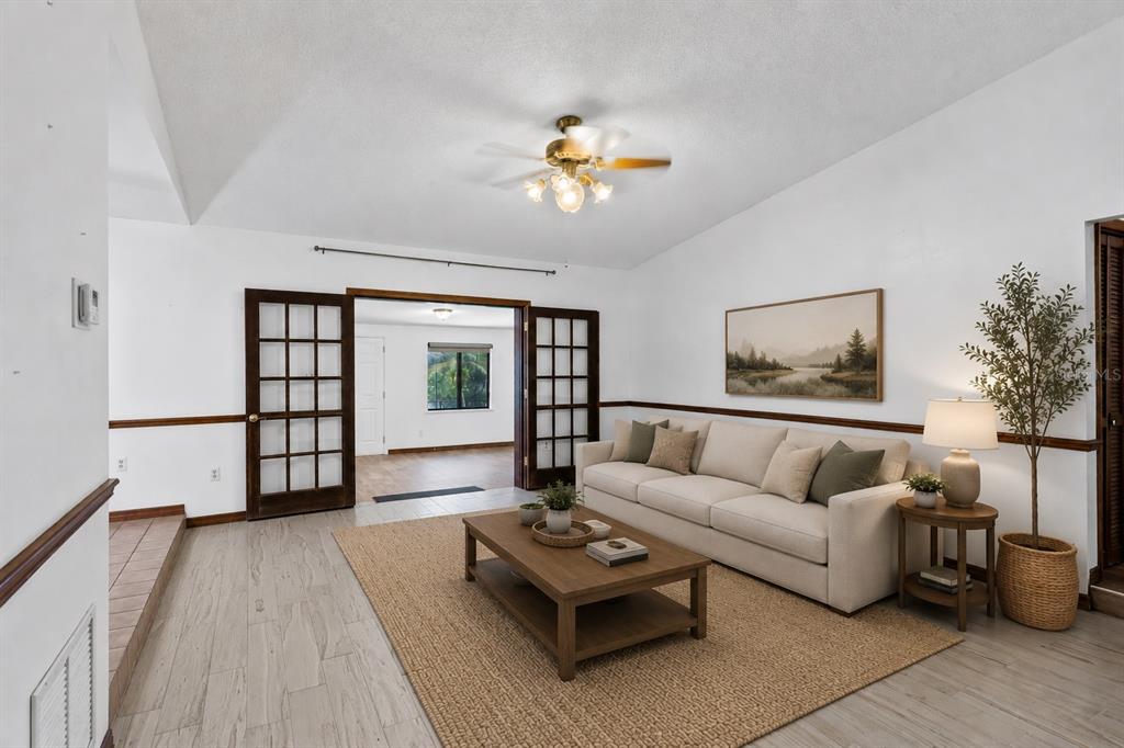 A living room features a beige sofa, wooden coffee table, and French doors leading outside — 17531 N SUNSET TERRACE, WINTER GARDEN, FL