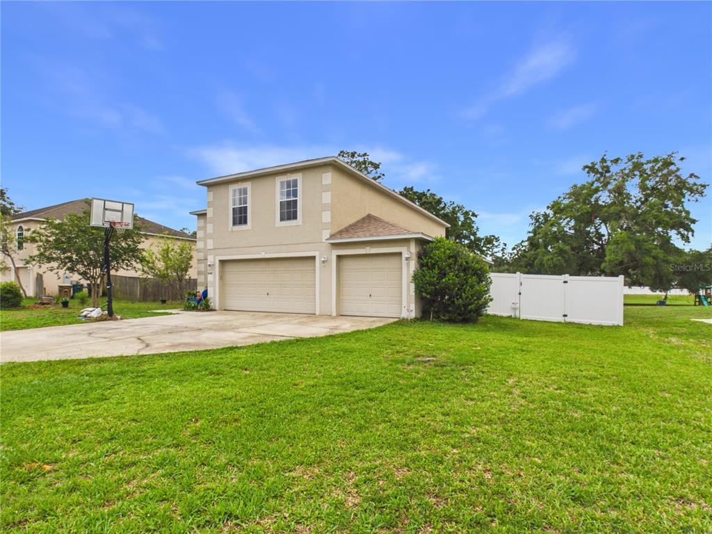 A two-story house with a three-car garage and a white vinyl fence in the yard — 4540 SE 30TH STREET, OCALA, FL