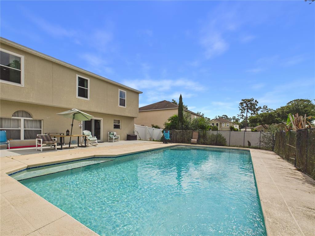 A backyard features a rectangular swimming pool with a concrete deck and a two-story house — 4540 SE 30TH STREET, OCALA, FL