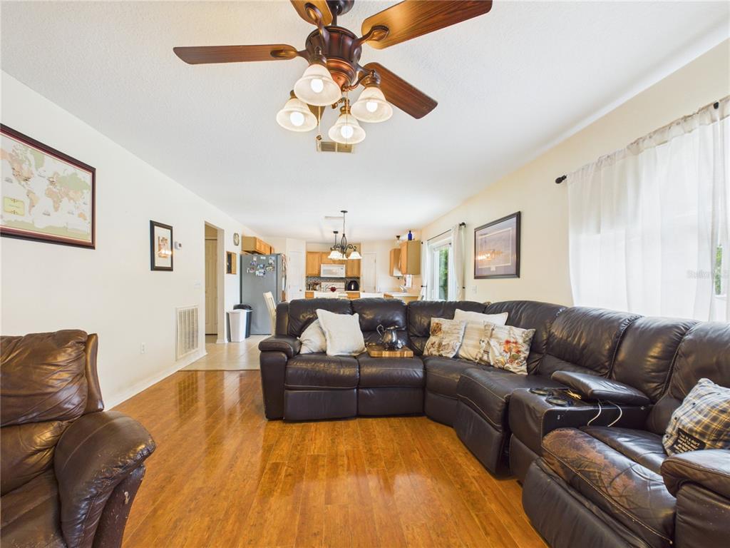 A living room features a large dark leather sectional, hardwood floors, and a ceiling fan — 4540 SE 30TH STREET, OCALA, FL