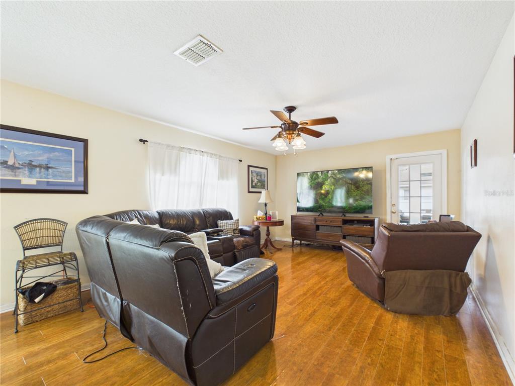 A living room with wood flooring, a leather sectional, a recliner, and a television console — 4540 SE 30TH STREET, OCALA, FL
