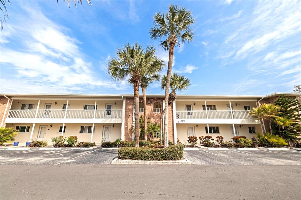 A two-story apartment building with a white exterior, balconies, and palm trees in the front — 4480 OVERLOOK DRIVE NE UNIT 10, ST PETERSBURG, FL