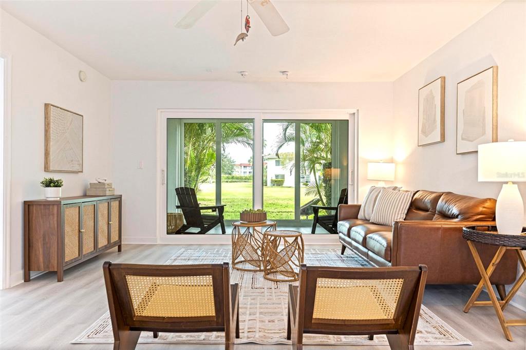 A living room features a brown leather sofa, two wooden chairs, and sliding glass doors — 4480 OVERLOOK DRIVE NE UNIT 10, ST PETERSBURG, FL