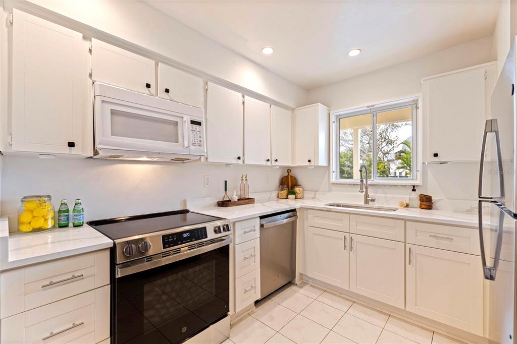 A kitchen features white cabinets, stainless steel appliances, and white countertops with a tiled floor — 4480 OVERLOOK DRIVE NE UNIT 10, ST PETERSBURG, FL