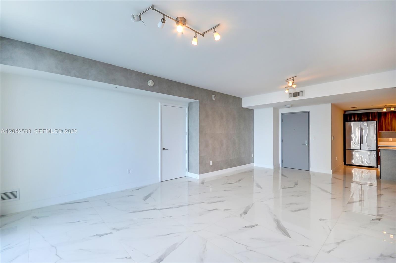 An open living area features white marble floors, gray accent walls, and a modern kitchen — 488 NE 18th St # 4310, Miami FL 33132, MIAMI, FL