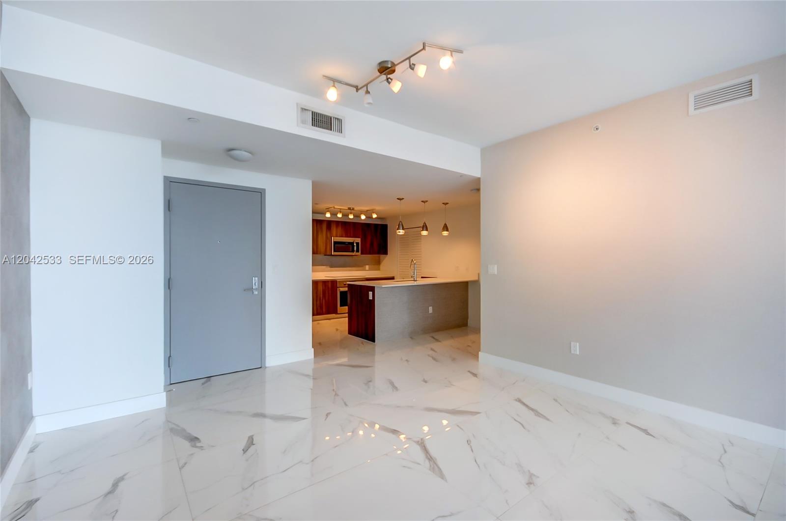 A living area with white marble floors leads to an open kitchen with wood cabinets — 488 NE 18th St # 4310, Miami FL 33132, MIAMI, FL