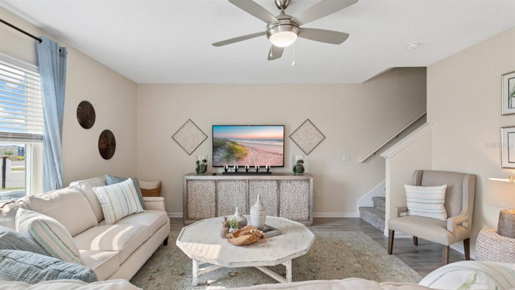 A living room features a beige sofa, an octagonal coffee table, and a wall-mounted television — 5221 WORCHESTER DRIVE, KISSIMMEE, FL