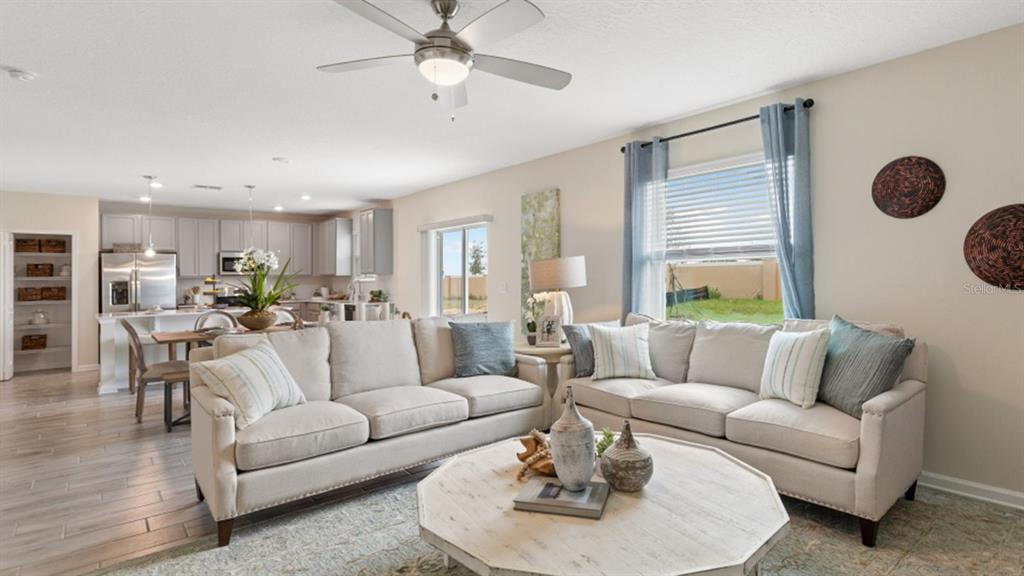 A living room with two beige sofas, a light wood coffee table, and an open kitchen — 5221 WORCHESTER DRIVE, KISSIMMEE, FL