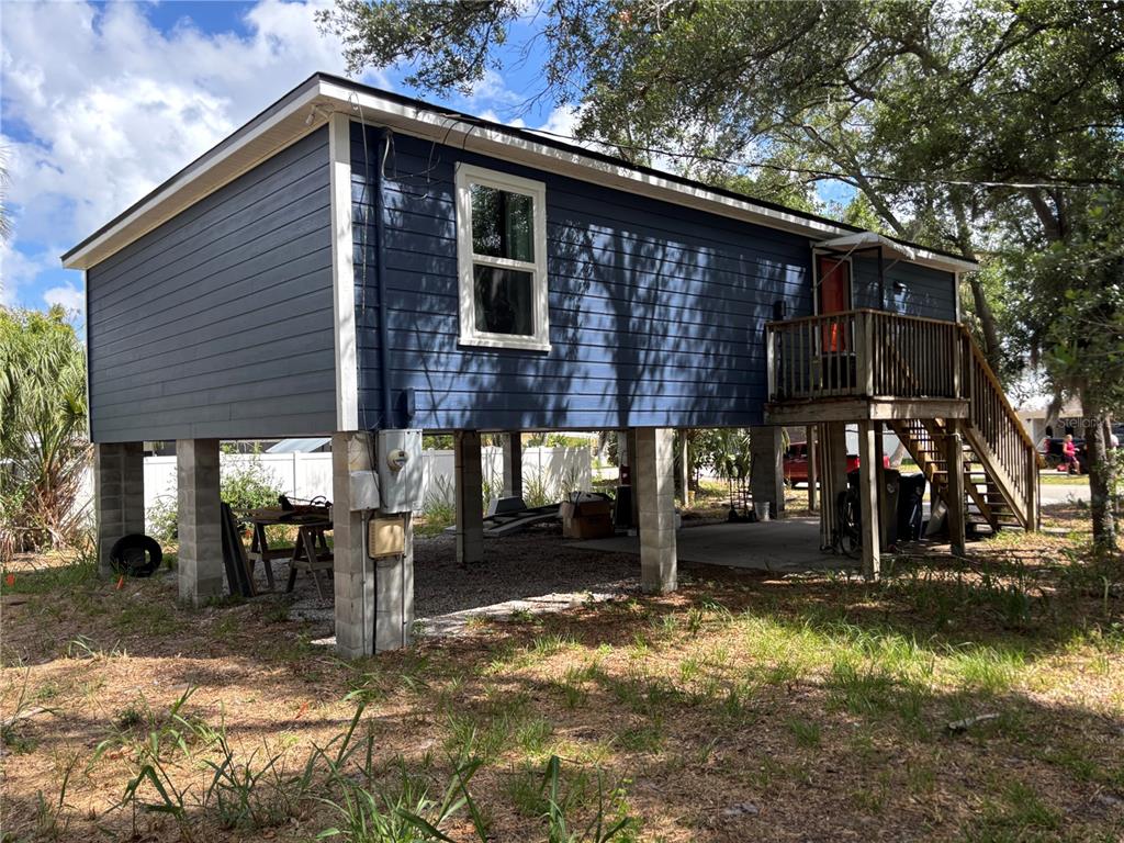 A blue elevated house stands on concrete block piers with an attached wooden staircase — 716 32ND STREET COURT E, BRADENTON, FL