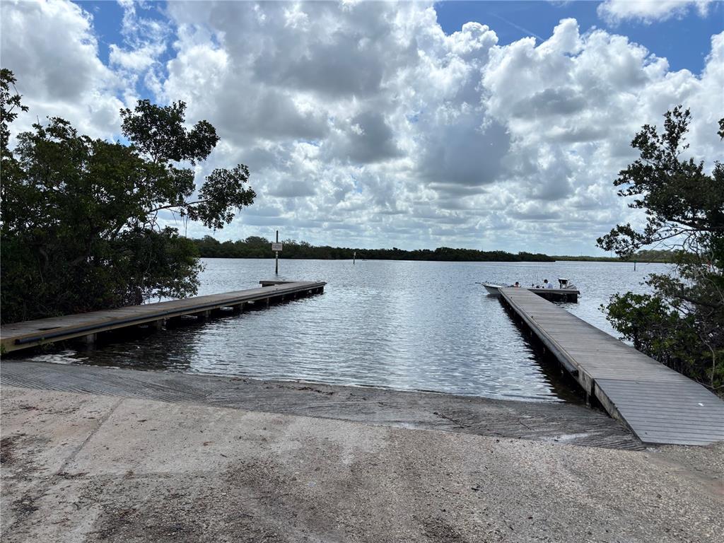 A concrete boat ramp leads into the water between two wooden docks — 716 32ND STREET COURT E, BRADENTON, FL