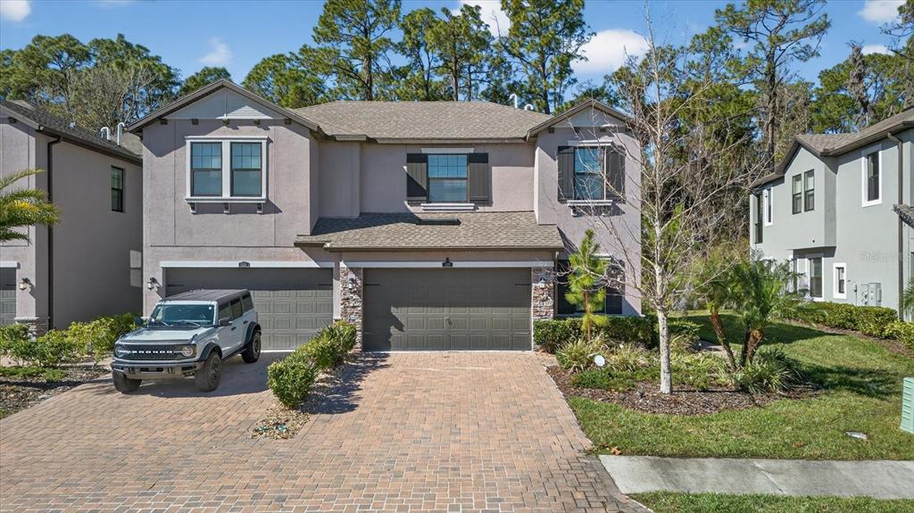 A two-story house with a paver driveway, a three-car garage, and a silver SUV parked outside — 5110 SAN MARTINO DRIVE, WESLEY CHAPEL, FL