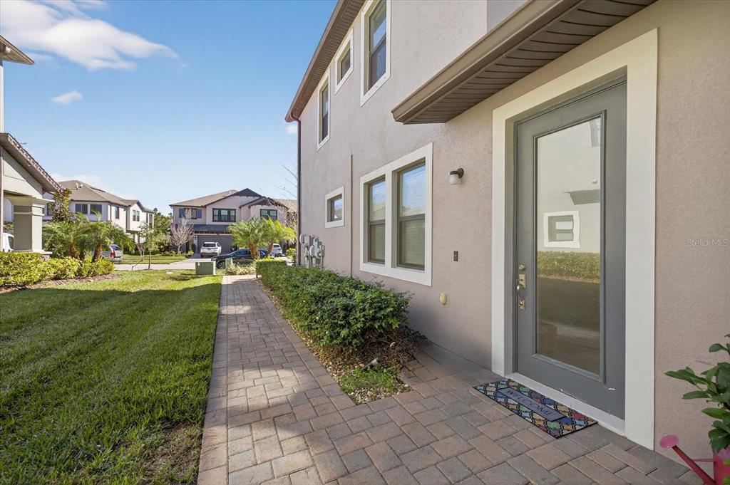 A paved walkway leads to the side entrance of a two-story stucco house — 5110 SAN MARTINO DRIVE, WESLEY CHAPEL, FL