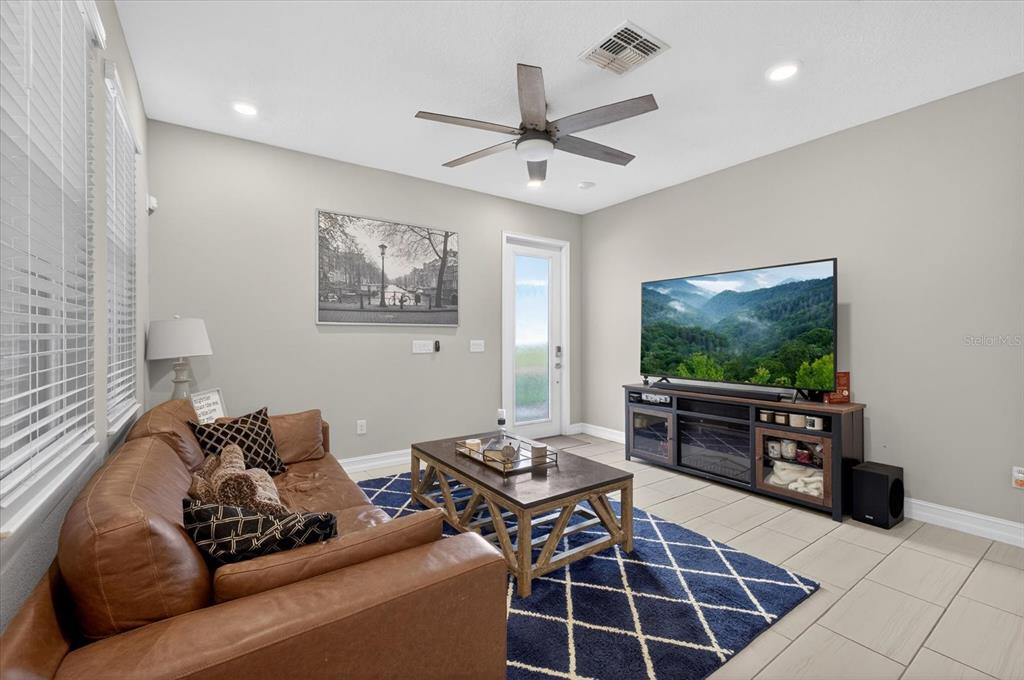 A living room features a brown leather sofa, a coffee table, and a television console — 5110 SAN MARTINO DRIVE, WESLEY CHAPEL, FL