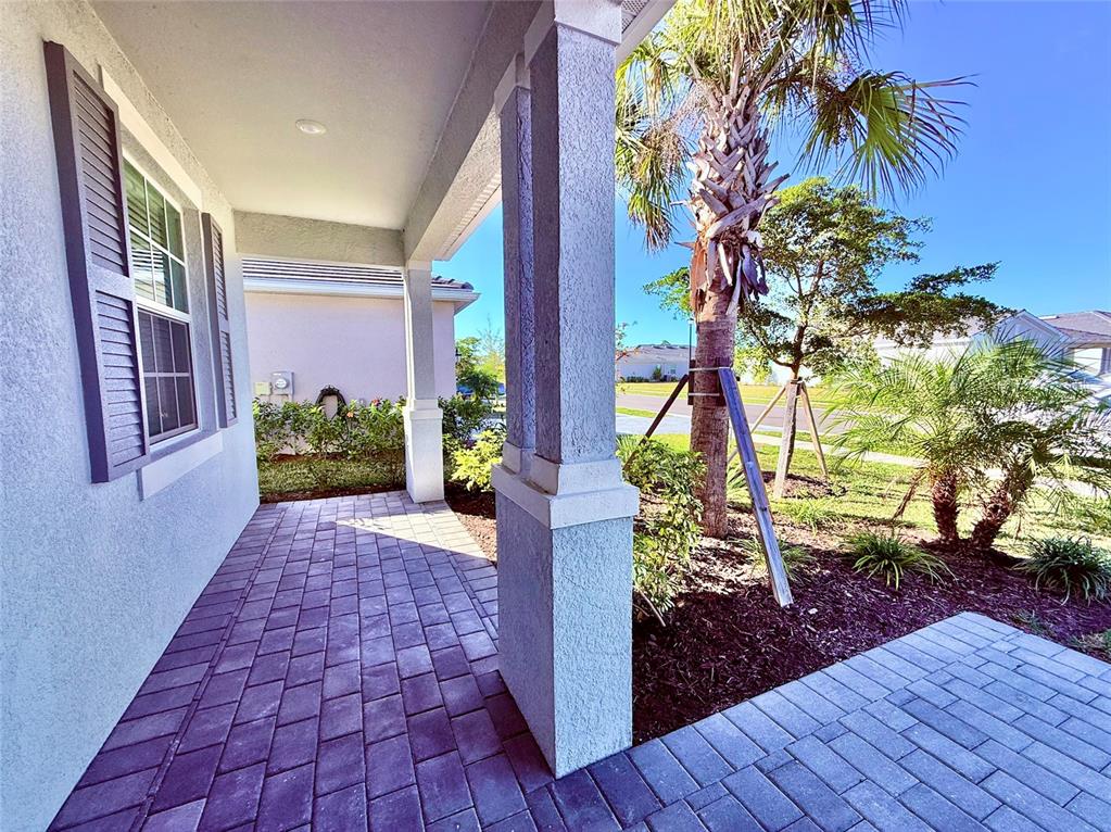 A paved front porch features a stucco column and a view of a palm tree — 10995 PINOT DRIVE, VENICE, FL