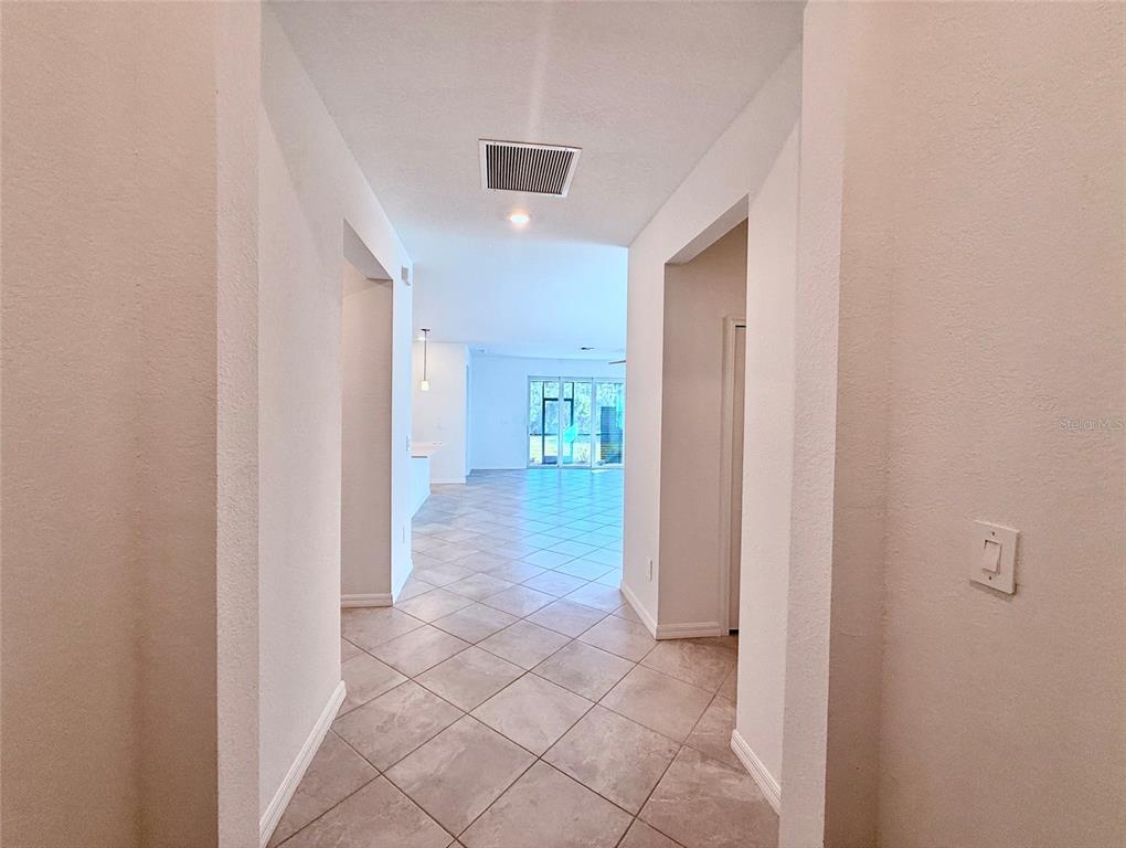 A tiled hallway leads to an open living area with large sliding glass doors — 10995 PINOT DRIVE, VENICE, FL