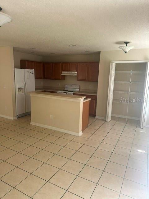 A kitchen with wood cabinets, a white refrigerator, a breakfast bar, and tiled flooring — 4525 WINDING RIVER WAY, LAND O LAKES, FL