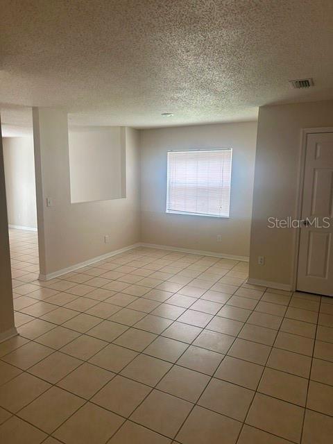 An empty room with light-colored tile flooring, a window with blinds, and a closed door — 4525 WINDING RIVER WAY, LAND O LAKES, FL