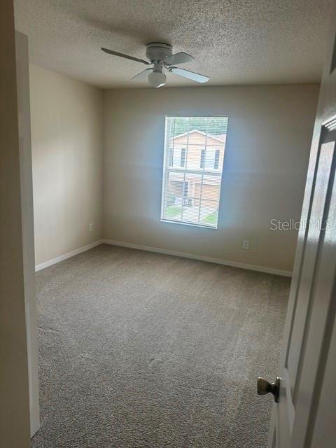 An empty bedroom features beige carpet, light-colored walls, a ceiling fan, and a single window — 4525 WINDING RIVER WAY, LAND O LAKES, FL