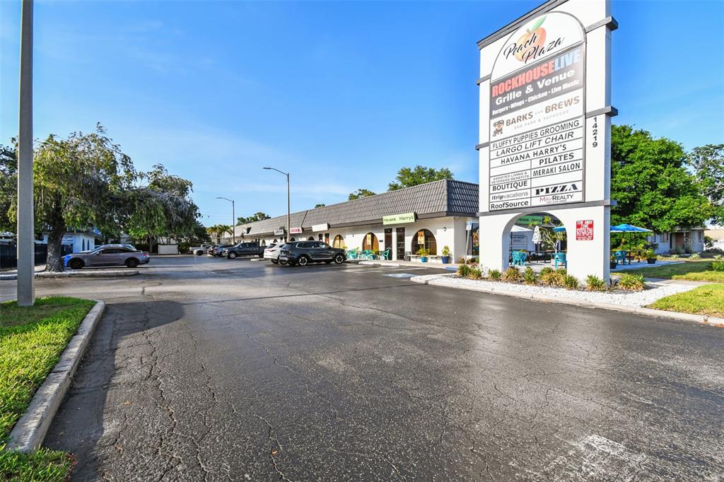 A parking lot sits in front of a commercial strip mall with a tall signage pylon — 14219 WALSINGHAM ROAD UNIT M, LARGO, FL