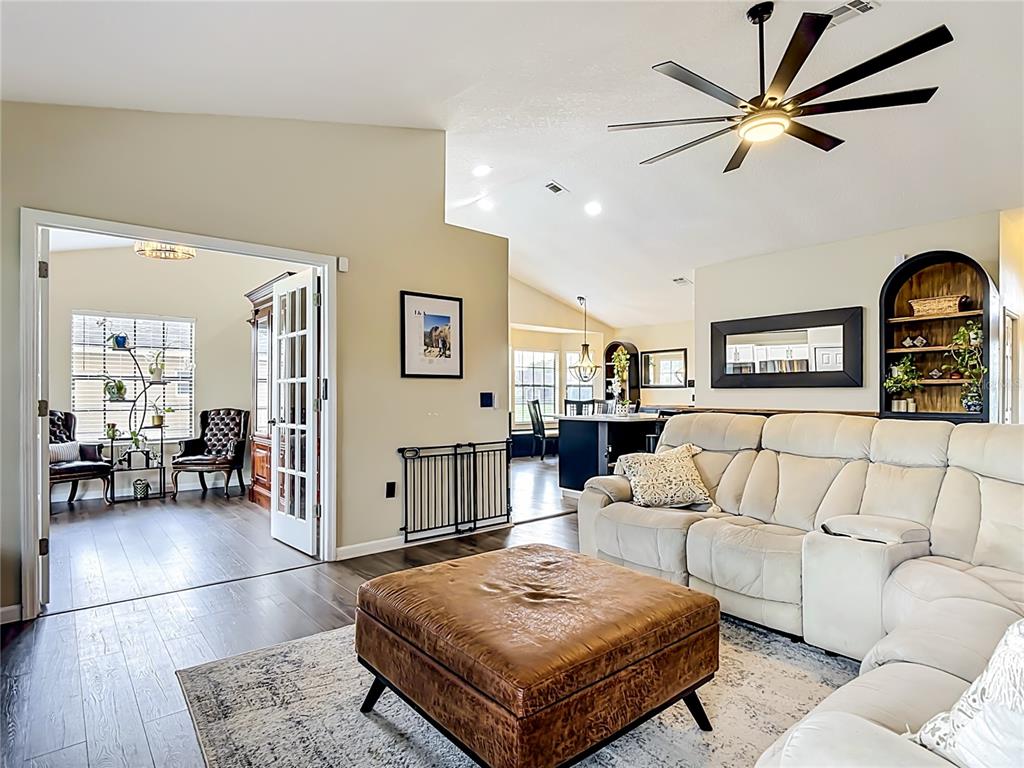 A living room features a white sectional sofa, leather ottoman, and an adjacent home office — 1393 WOOD LAKE CIRCLE, ST CLOUD, FL