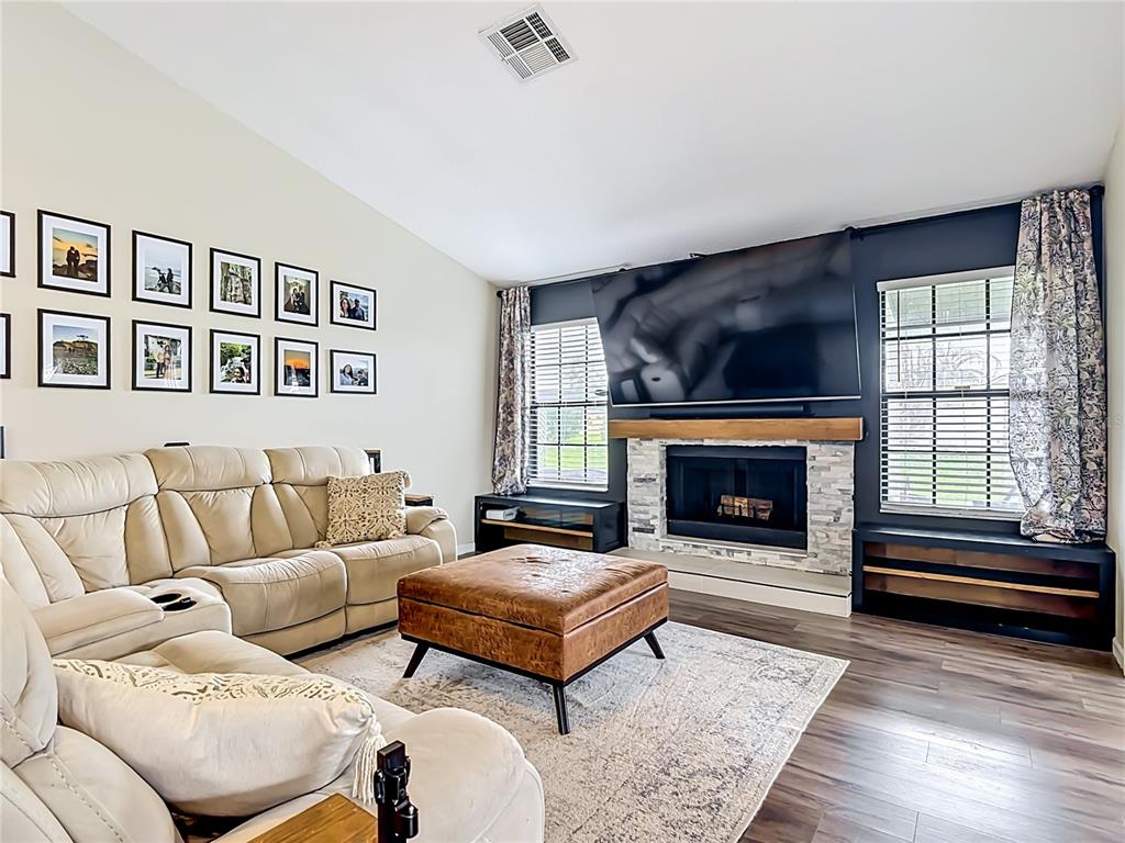 A living room features a stone fireplace, a large television, and a beige sectional sofa — 1393 WOOD LAKE CIRCLE, ST CLOUD, FL