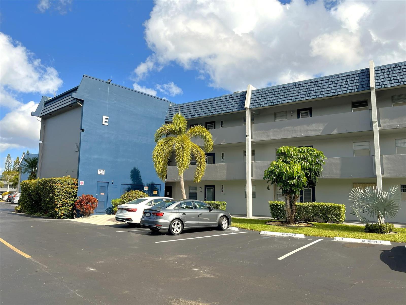 A blue and gray multi-story apartment building with a parking lot and palm trees — 7837 Golf Circle Drive # 206, Margate FL 33063, MARGATE, FL