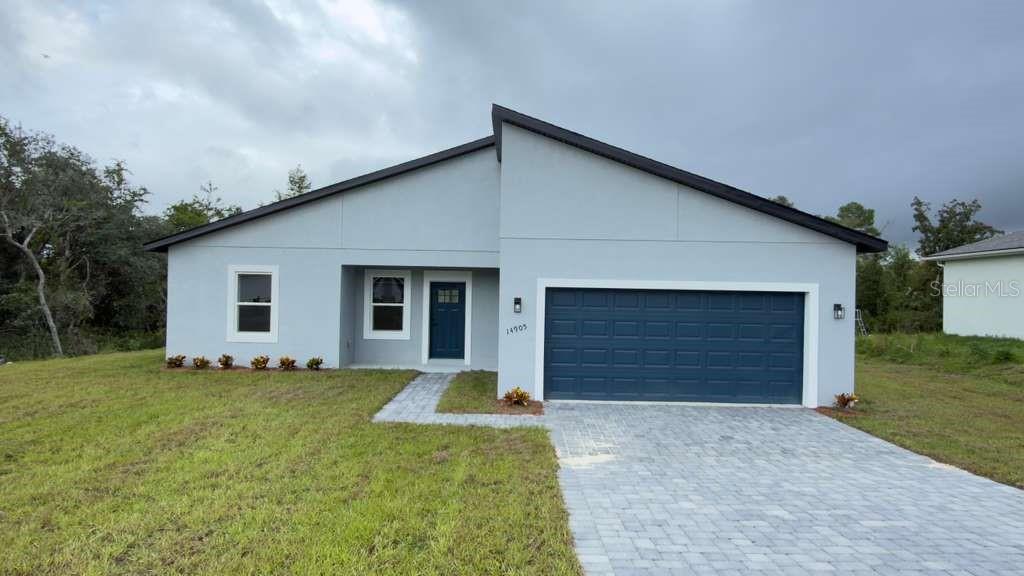 A single-story house with a light gray exterior, dark blue garage door, and paved driveway — 14905 SW 24TH CIRCLE, OCALA, FL