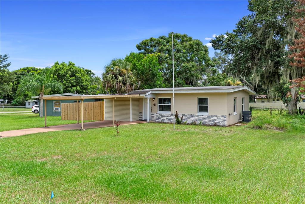 A single-story house with a beige exterior, stone accents, and an attached carport — 460 E 3RD STREET, CHULUOTA, FL