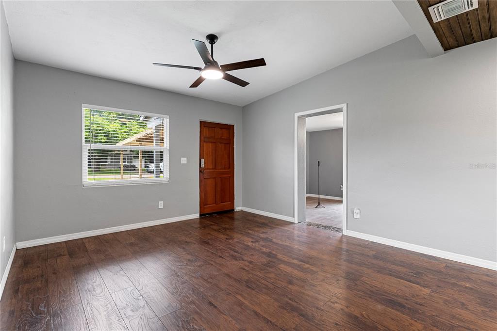 A room with gray walls, dark wood-look flooring, a ceiling fan, and a wooden door — 460 E 3RD STREET, CHULUOTA, FL