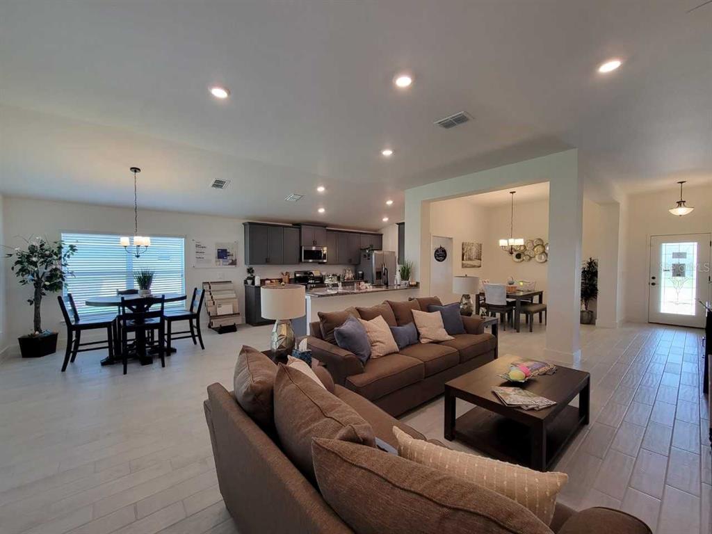 An open-concept living room and kitchen area with light tile flooring and brown furniture — 4447 SW 91ST LANE ROAD, OCALA, FL