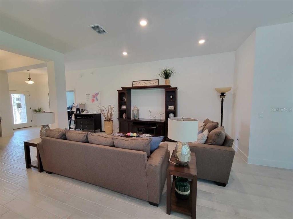 A living room features a large brown sectional sofa, a dark wood entertainment center, and tile flooring — 4447 SW 91ST LANE ROAD, OCALA, FL
