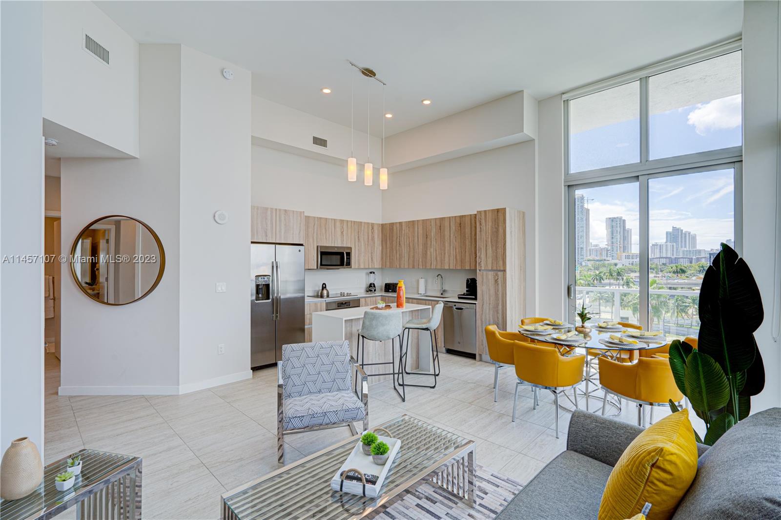A modern open-concept kitchen and dining area features light wood cabinetry and floor-to-ceiling windows — 3900 Biscayne Blvd # 502, Miami FL 33137, MIAMI, FL