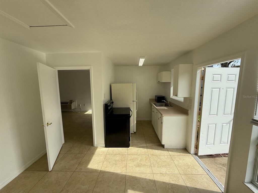 A kitchen with tile flooring, white cabinets, a black stove, and a white refrigerator — 316 MANGO DRIVE UNIT B, DAVENPORT, FL