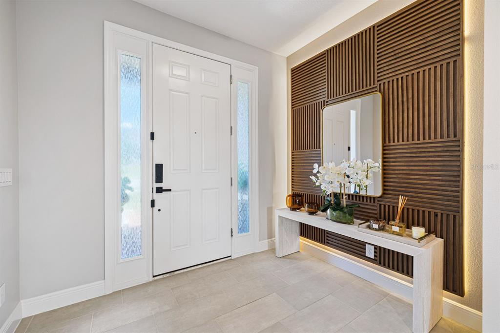An entryway features a white front door with sidelights, a wood slat accent wall, and a console — 399 CHEEOTA COURT, MINNEOLA, FL
