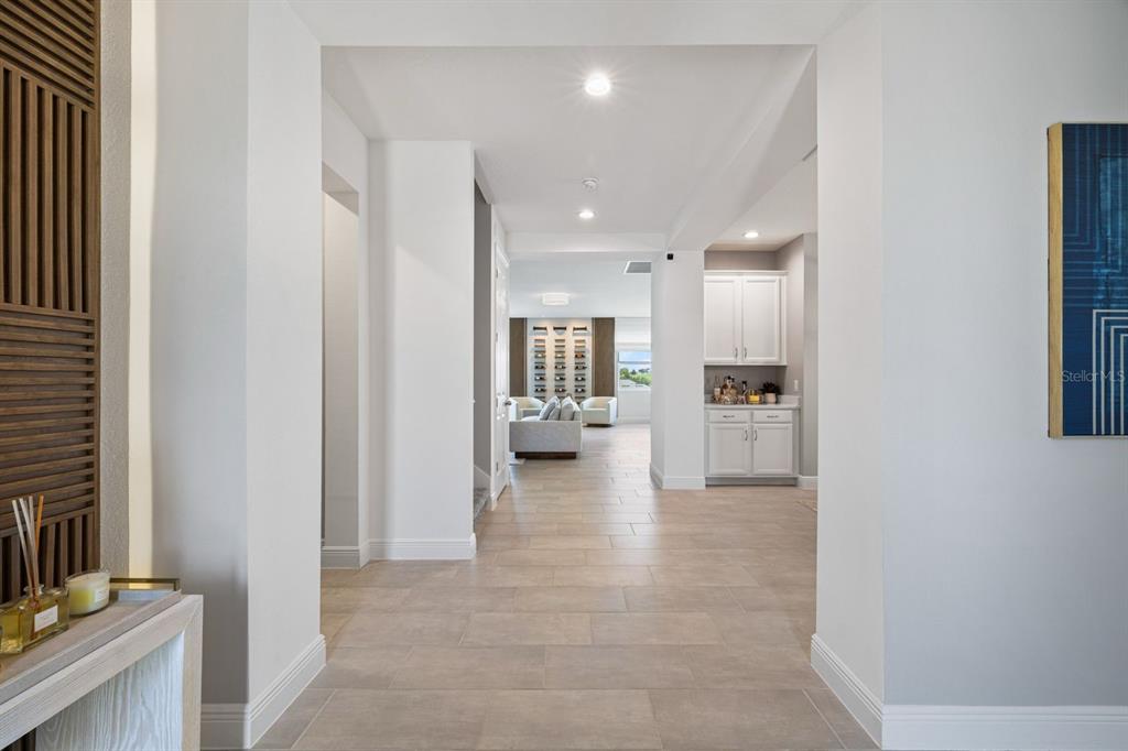 A tiled hallway leads to a living area with a wet bar and white cabinetry — 399 CHEEOTA COURT, MINNEOLA, FL