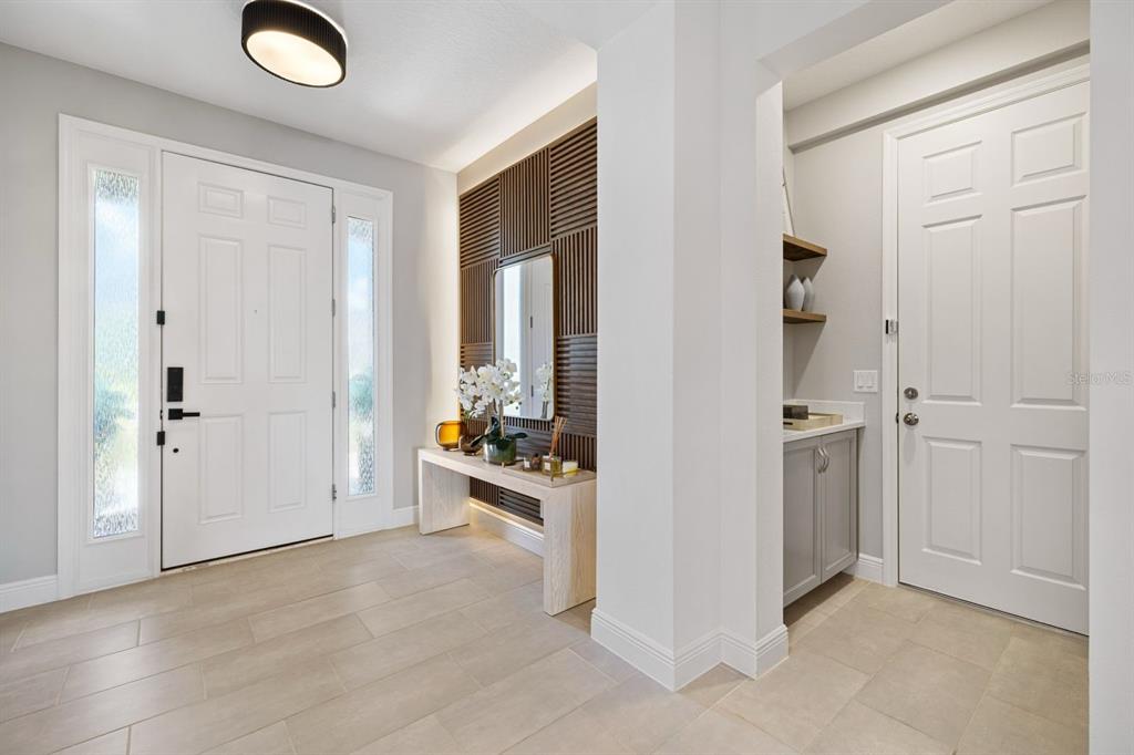 An entryway features a white front door, a slatted wood accent wall, and tile flooring — 399 CHEEOTA COURT, MINNEOLA, FL