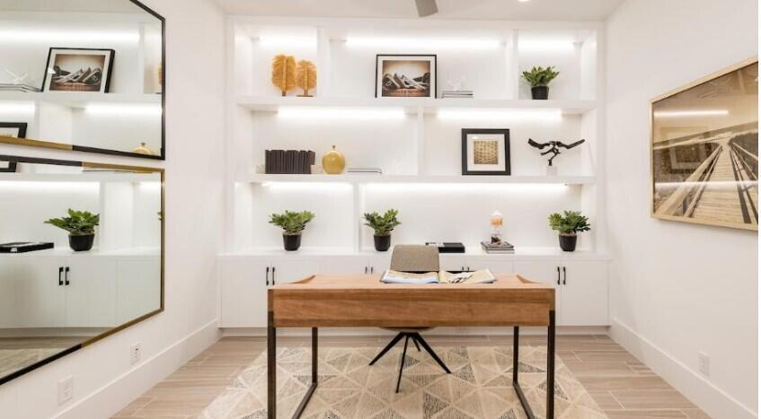 A home office features a wooden desk, built-in white shelving with lighting, and wall mirrors — 9854 Regency Way, Palm Beach Gardens FL 33412, PALM BEACH GARDENS, FL