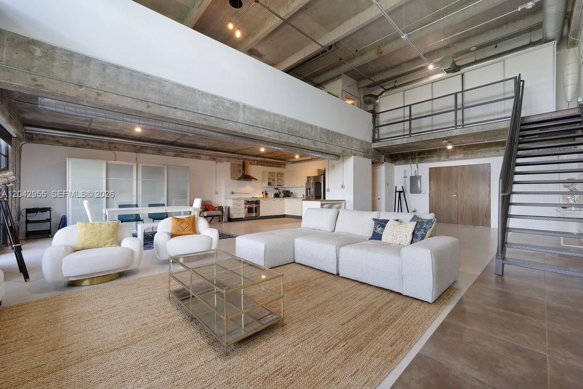 This open-concept loft features a concrete ceiling, a metal staircase, and a modern kitchen — 1749 NE Miami Ct # 507, Miami FL 33132, MIAMI, FL
