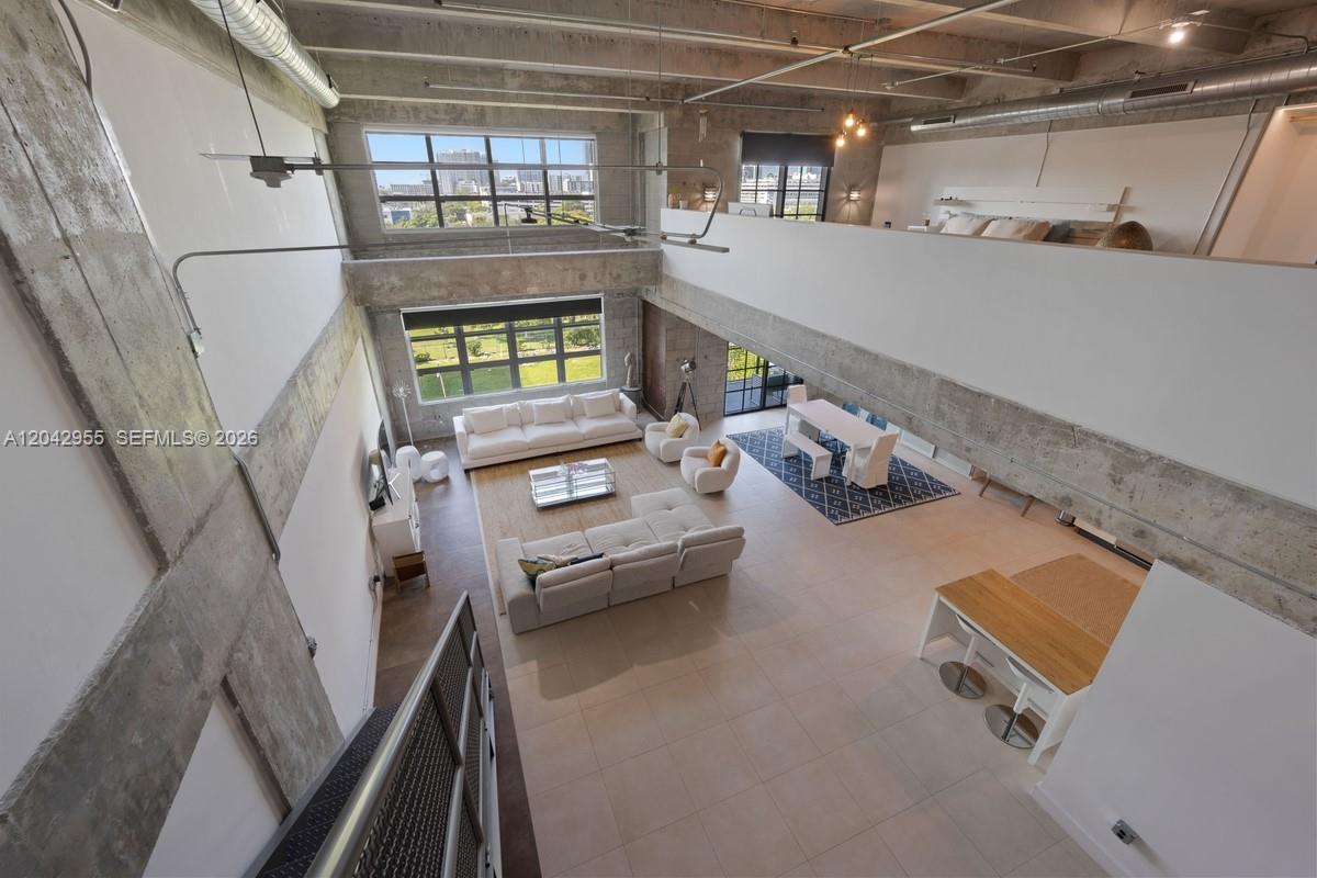 A high-angle view of a modern industrial-style loft with concrete walls, exposed ceilings, and mezzanine — 1749 NE Miami Ct # 507, Miami FL 33132, MIAMI, FL