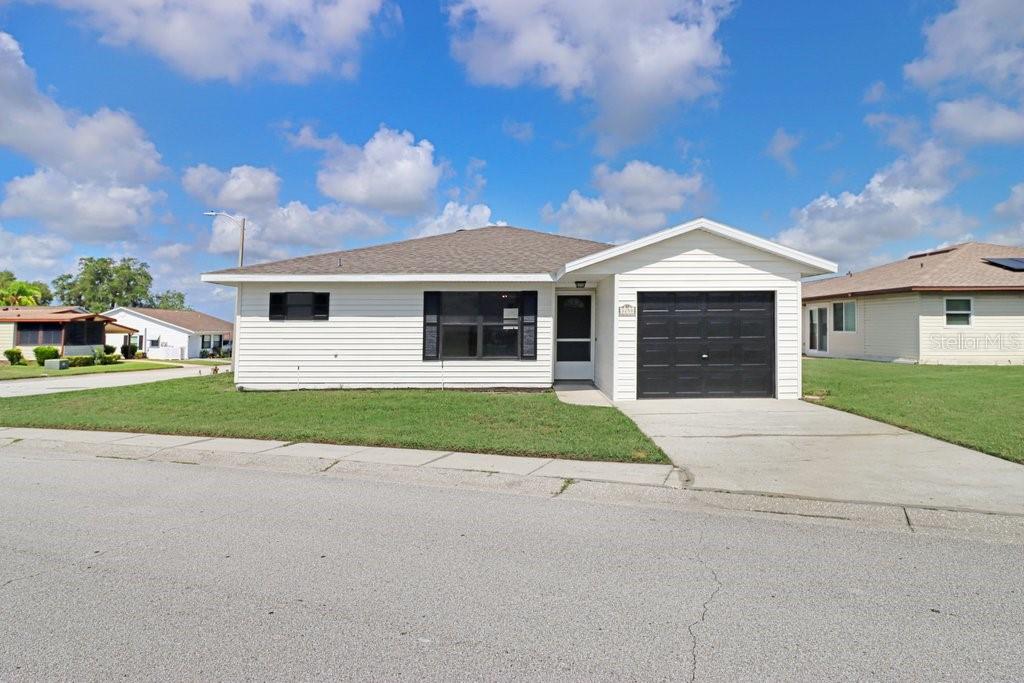 A single-story white house with a black garage door and a grassy front yard — 3250 PEBBLE BEND DRIVE, LAKELAND, FL