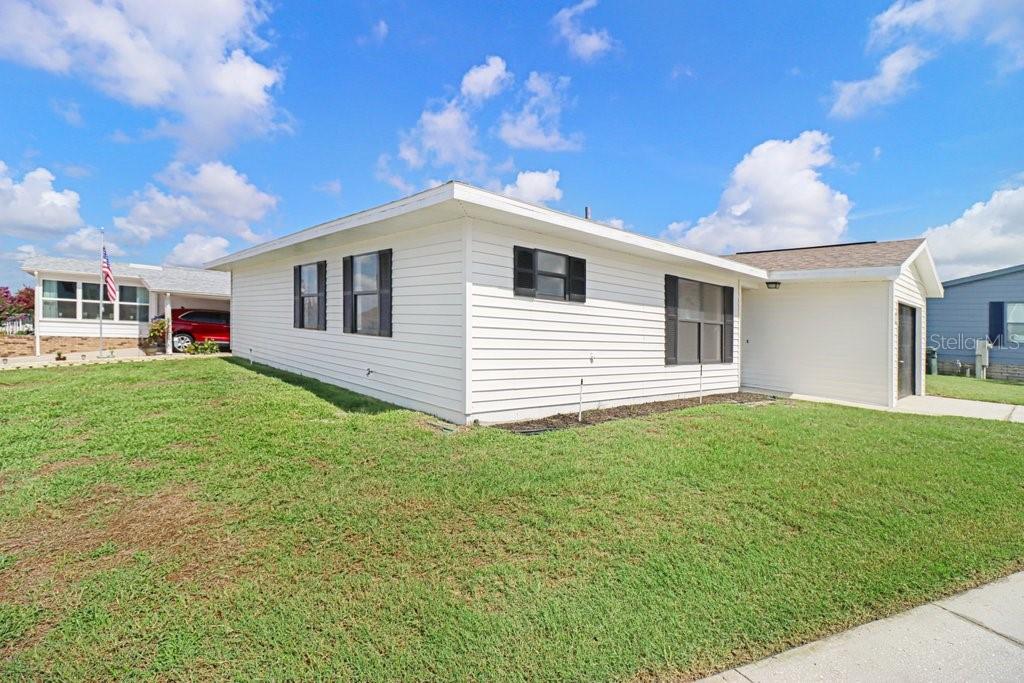 A white single-story house with horizontal siding and a shingled roof sits on a lawn — 3250 PEBBLE BEND DRIVE, LAKELAND, FL