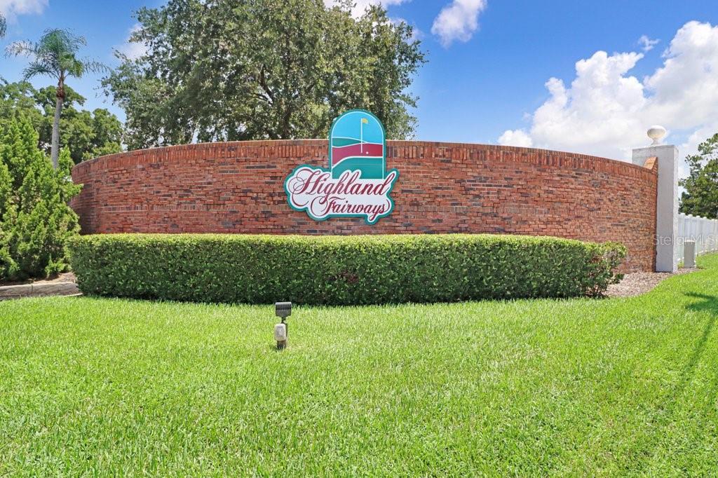 A brick entrance sign for Highland Fairways sits behind a manicured hedge and lawn — 3250 PEBBLE BEND DRIVE, LAKELAND, FL