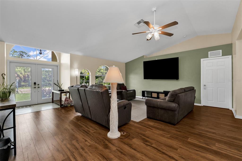 A living room features brown leather furniture, a green accent wall, and wood-look flooring — 4413 S SAN MATEO DRIVE, NORTH PORT, FL