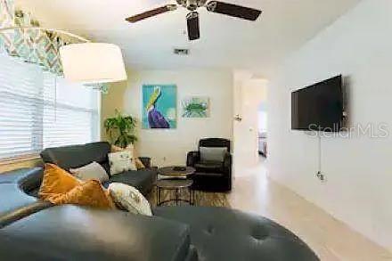 A living room features a dark leather sectional, a black armchair, and a wall-mounted television — 210 57TH STREET W, BRADENTON, FL