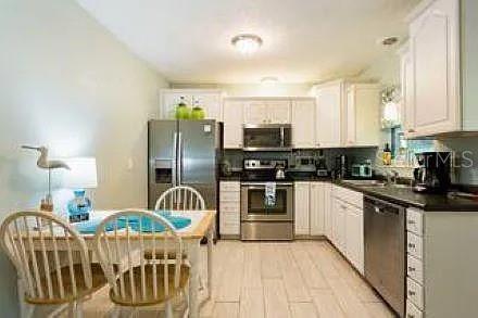 A kitchen with white cabinets, stainless steel appliances, and a dining table with four chairs — 210 57TH STREET W, BRADENTON, FL