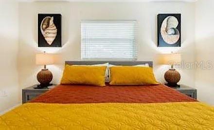 A bedroom features a bed with yellow and orange bedding, two lamps, and shell artwork — 210 57TH STREET W, BRADENTON, FL