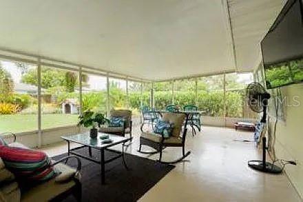 A screened-in patio features a seating area with rocking chairs, a coffee table, and views — 210 57TH STREET W, BRADENTON, FL
