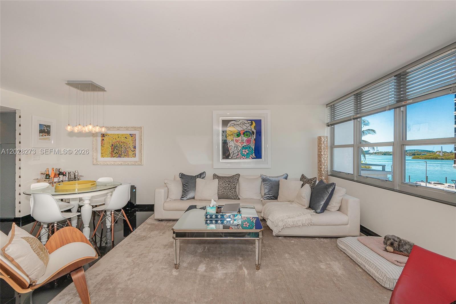 A living and dining area features a sectional sofa, glass-topped tables, and waterfront window views — 11 Island Ave # 409, Miami Beach FL 33139, MIAMI BEACH, FL