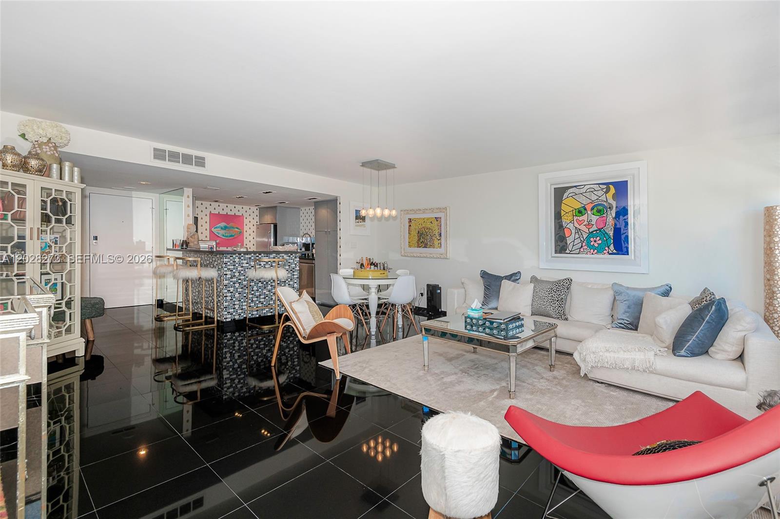 An open-concept living and dining area features black tile flooring and a kitchen bar — 11 Island Ave # 409, Miami Beach FL 33139, MIAMI BEACH, FL